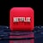 A red, cube-shaped icon with the word 'NETFLIX' prominently displayed in white, bold letters. The cube is set against a dark, glossy, circular patterned background, reflecting a sleek, futuristic design.